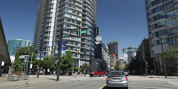 Vancouver, Canada - July 1, 2022: Traffic and pedestrians share the intersection at Pat Quinn Way and Expo Boulevard. View looking north to the modern residential buildings lining Abbott Street in the south end of Chinatown.