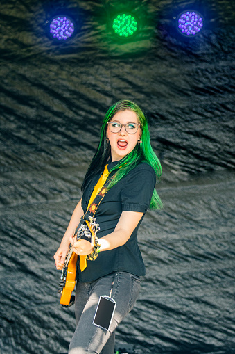 A beautiful 20 year old with green hair playing bass live with her pop punk band.