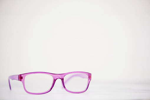 Modern pink eyeglasses shot in a bright setting with space for text