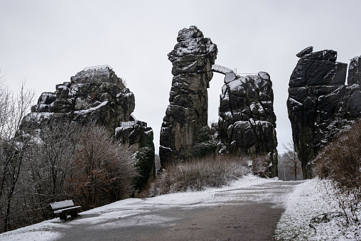Externsteine rock formation covered in snow on a cloudy winter day, Teutoburg Forest, Germany