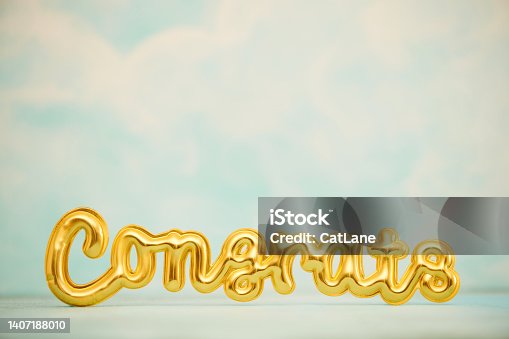 istock CONGRATULATIONS message in gold against blue sky with lots of space for copy 1407188010