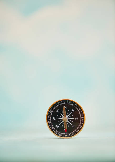 Compass in a bright setting with lots of copy space and clouds in the background