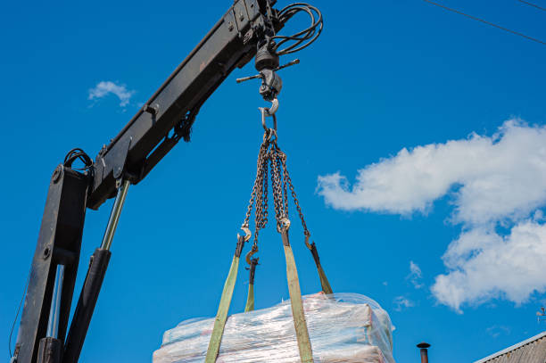 istock Unloading paving slabs from a truck. Men unload paving slabs using a manipulator. Workers unload building materials from a large machine. 1407190471