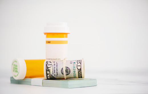 Cost of medication. Pill bottles with dollars and space for copy