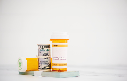 Cost of medication. Pill bottles with dollars and space for copy