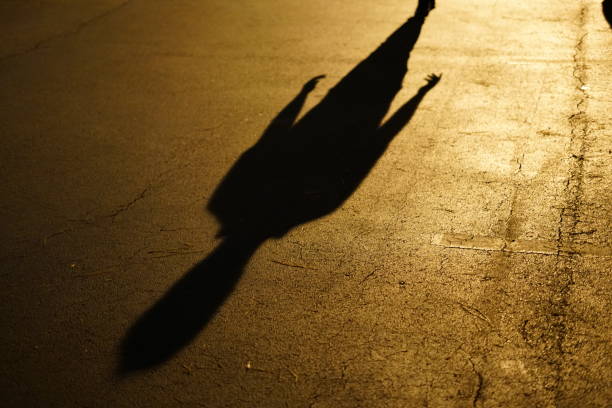 istock Elongated shadow of man upon pavement and yellow reflection. 1407190651
