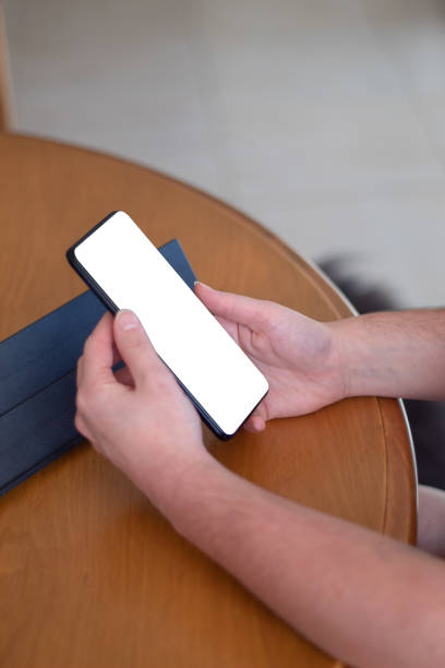 istock Hands holding cell phone with blank screen on wooden table 1407190704