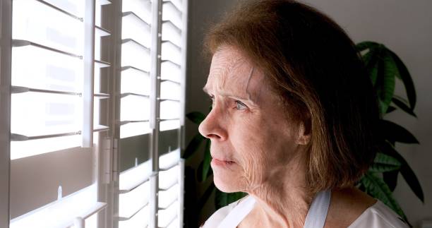 istock Serious, worried, stressed senior woman looking through a window 1407194870