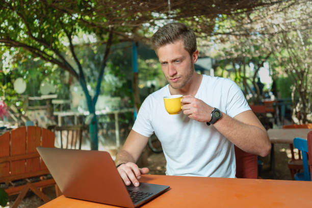 istock Young Man working with laptop outdoor in a beautiful terrace using smartphone and computer sitting cross-legged in Home work. 1407194968