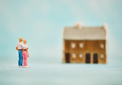 Miniature figures of a young couple looking at a home