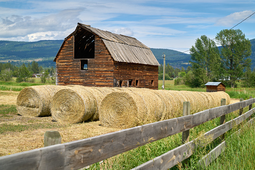 Old wooden hayloft or haymow. Rural landscape with village road and barn for hay. Agricultural building in countryside.