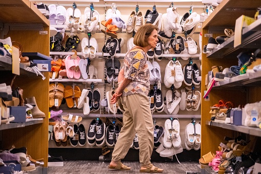 Caucasian Senior woman scared of prices because inflation while shopping for shoes at a department store