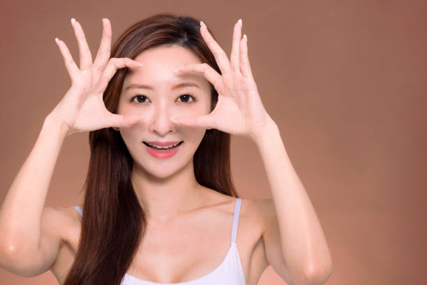 Young beautiful  woman  doing ok gesture with hand smiling, eye looking through fingers with happy face. stock photo