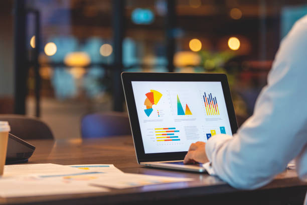 close up of businessman using a laptop with graphs and charts on a laptop computer. - relatório imagens e fotografias de stock