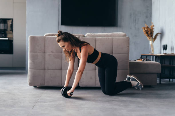 istock Fit woman working out with ab exercise wheel at home. 1407209224