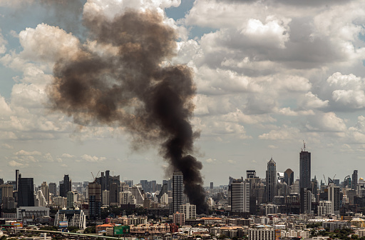 Bangkok, Thailand - 21 Jun, 2022 : Plume of black smoke clouds from burnt building on fire at community area in the bangkok city. Fire disaster accident, No focus, specifically.