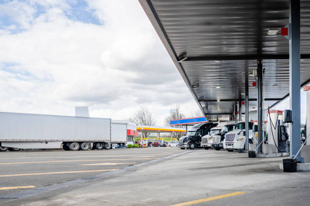 Big rigs semi trucks with semi trailers standing on the truck stop fuel station refueling tanks for freights continuation stock photo