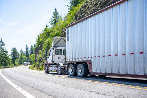 istock Two big rigs semi trucks with different semi trailers running towards each other on the winding mountain road with cliff and trees 1407216692