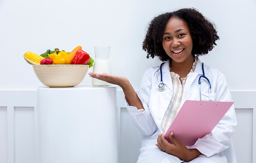 Portrait of African American nutritionist with bowl of variety of fruit and vegetable for healthy diet and vitamin booster