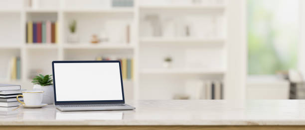 istock Tabletop with notebook laptop mockup and copy space over blurred modern office room in background. 1407221222