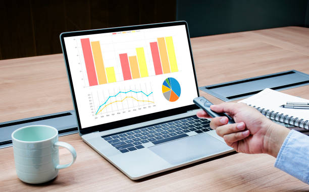 istock Businessman hand hold remote control slide with mock up chart slide show presentation on display laptop on table 1407222643