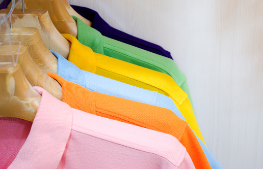 Many colorful shirts hanging on a rack