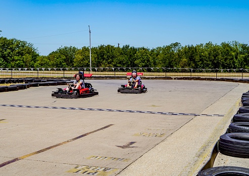 A teen boy leads while racing his grandfather in go-carts. Copy Space.