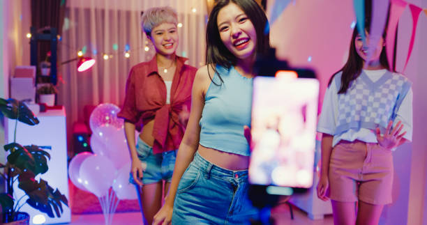 junge asiatische freundinnen tiktok erstellte ihr tanzvideo per smartphone und amüsierte sich nachts auf einer bunten hausparty. - asian culture dancing women people stock-fotos und bilder