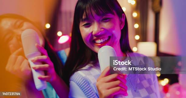 Close Up Of Young Asian Female Friends Singing Karaoke Having Fun At Colorful House Party At Night Stock Photo - Download Image Now
