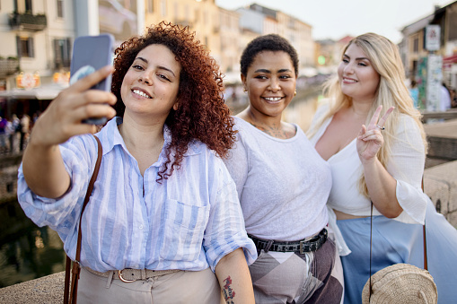 Female friends city touring and taking selfie in Navigli District
