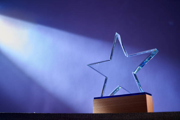 forma de estrella del trofeo de cristal sobre fondo púrpura - award fotografías e imágenes de stock