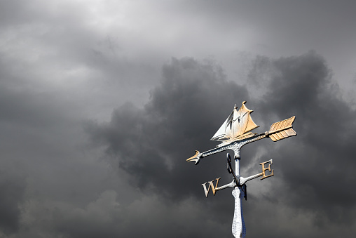 Sailboat weather vane against storm clouds with copy space.