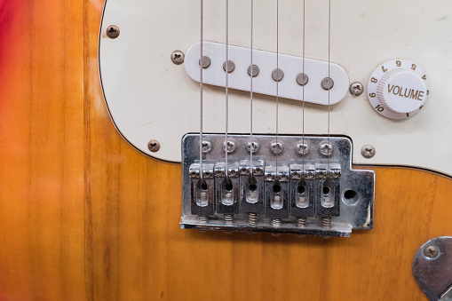 Vintage electric bass of four strings plugged into speaker in interior place. Amplifier with blur effect with bass in the background. Playing in home.