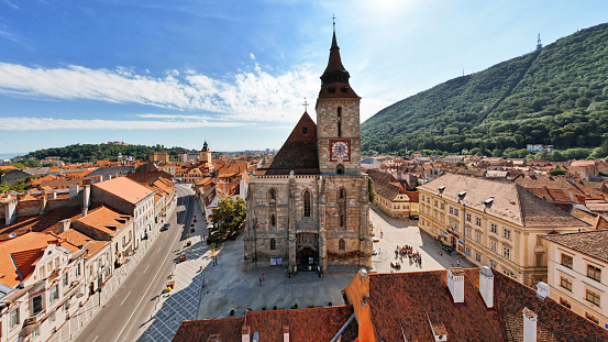 Aerial drone view of the The Black Church in old Brasov centre, Romania. Old residential buildings around it, hills with greenery