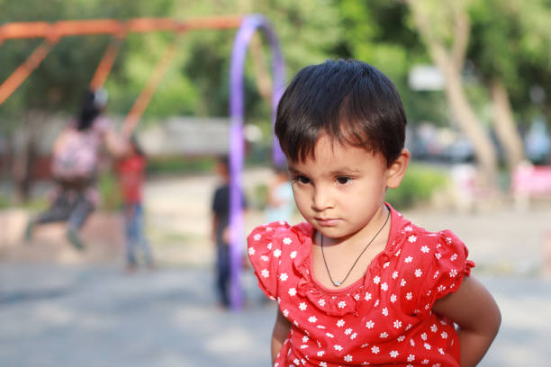 Small baby girl playing outdoors in public park.