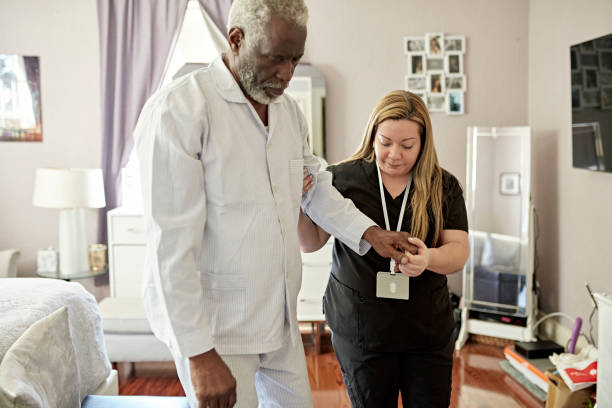 istock Female home caregiver helping senior client with first steps 1407245279