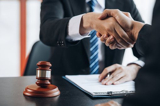 Lawyers shake hands with clients who come to testify in the case of embezzlement from business partners who jointly invest in the business. The concept of hiring a lawyer for legal proceedings.