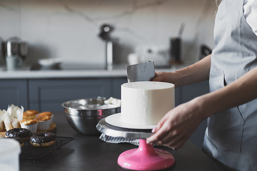 Young lovely woman pastry chef preparing a festive cake at home in the kitchen Small business, homemade pastry chef