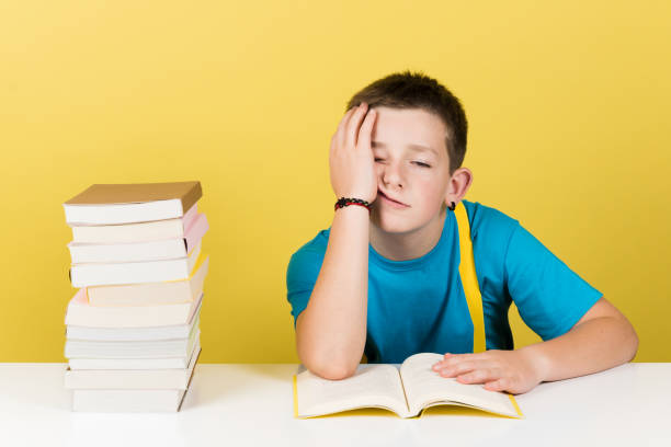 istock Demotivated boy reading book isolated on yellow background. 1407248954