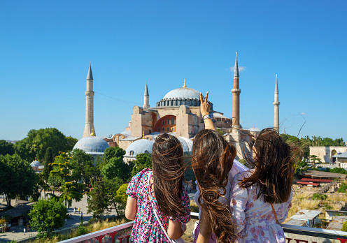 Portrait of cheerful girlfriends posing in front of Hagia Sophia Mosque in Istanbul, Turkey