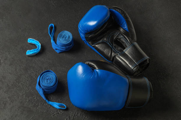 istock Blue boxing gloves with a cap and bandages on a black background 1407250378