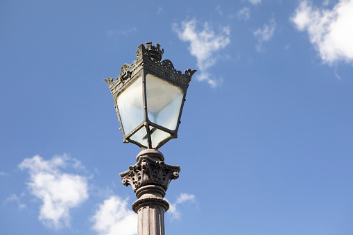 A vertical shot of a lamppost in a park under a cloudy sky