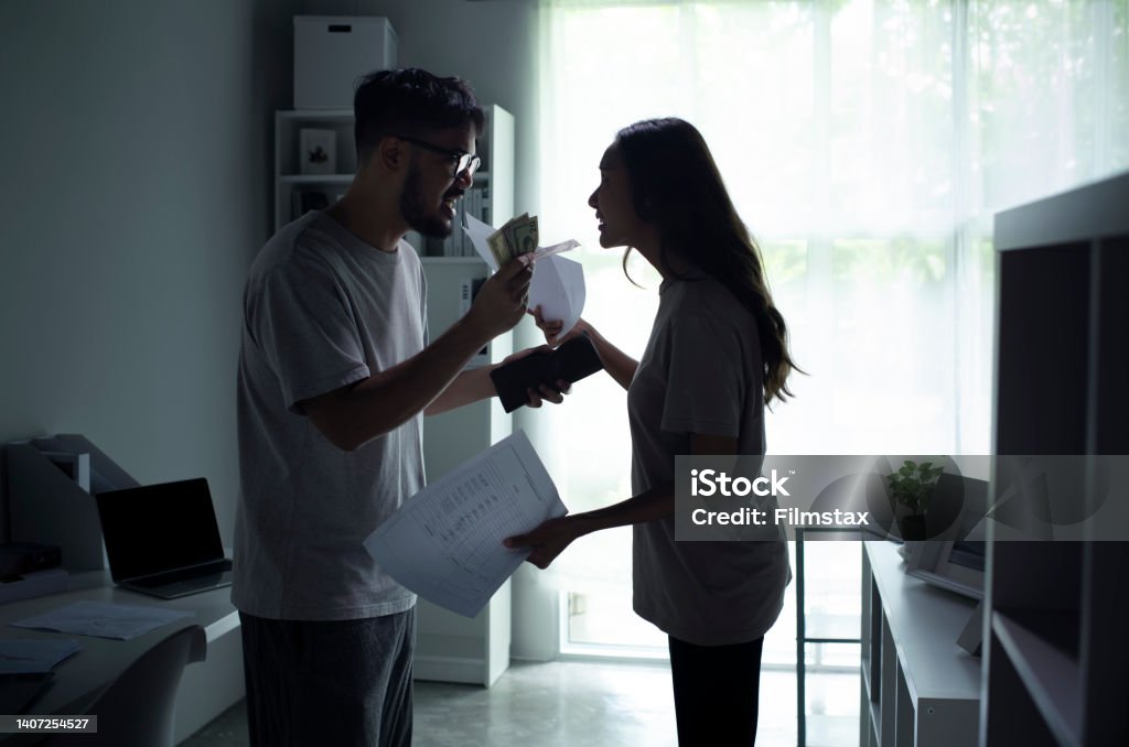Asian couple arguing about money at home. Asian couple arguing about money at home, husband and wife shouting in a hard quarrel by their many debts at home, financial family problems concept. Couple - Relationship Stock Photo