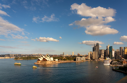 Sydney, Australia - August 2, 2019: Ferries crosses the waters of Circular Quay in Sydney. In the background looms the iconic form of the city's famous Opera House.