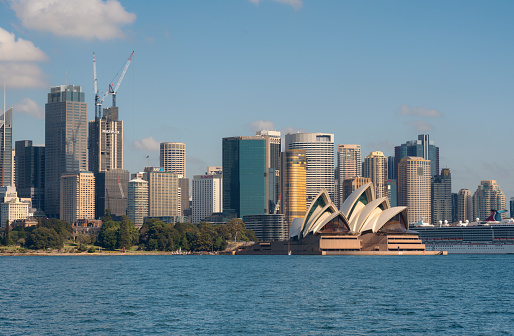 Sydney Australia - August 5, 2019: The spectacular cityscape around Sydney Harbour, Australia. The cruise ship Carnival Spirit is moored at the Overseas Terminal next to Circular Quay. Across the water we see the iconic form of the Sydney Opera House and beyond that the Royal Botanic Gardens.