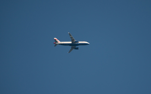 Buckinghamshire, UK - June 22, 2022: Low angle view of a British Airways A-320 aeroplane in flight in a clear blue sky.