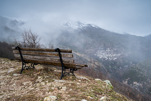 Sitting bench by the mountain with misty view of the traditional village of Syrrako at Tzoumerka Greece