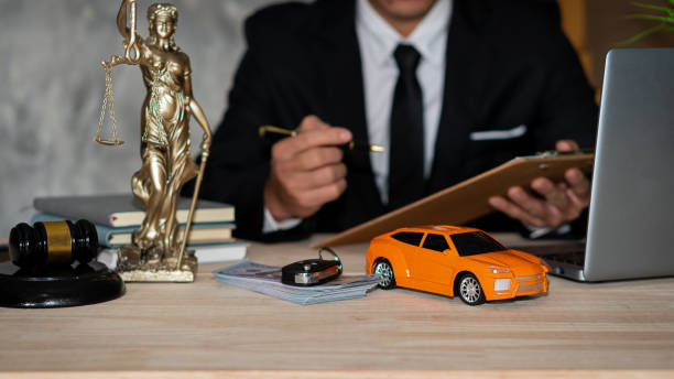 Small cars, keys and scales. Goddess of justice with hammer, money and laptop, and businessman holding a pen to sign a contract under car title approval concept. stock photo