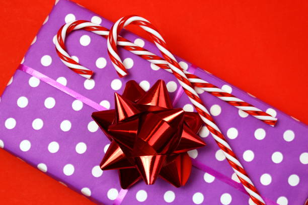 coffret cadeau avec une canne sucrée sur fond rouge. - christmas crutch holiday christmas decoration photos et images de collection