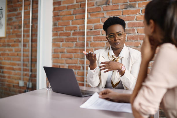 Black businesswoman talking to a candidate during job interview in the office. African American businesswoman communicating with female job candidate during a meeting in the office. coach stock pictures, royalty-free photos & images